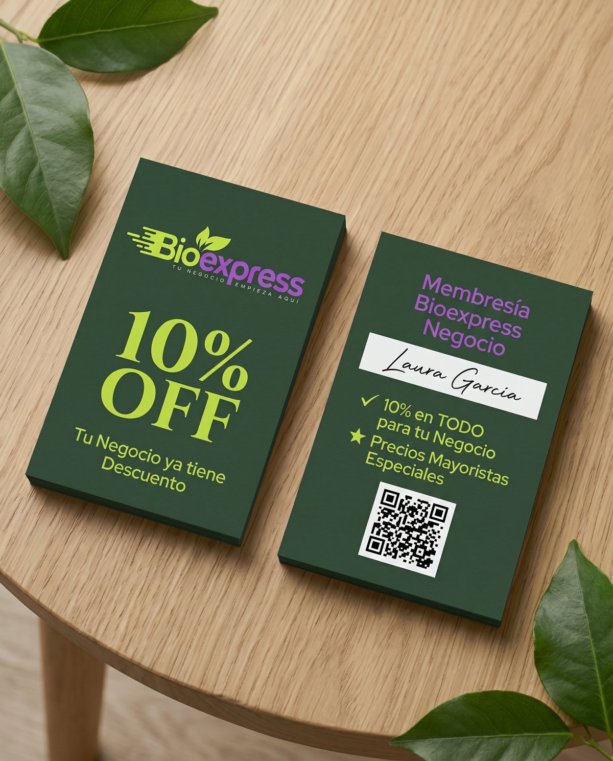 Two green business cards for BioExpress displayed on light wood with green leaves, showing 10% off promotion and membership details with QR code
