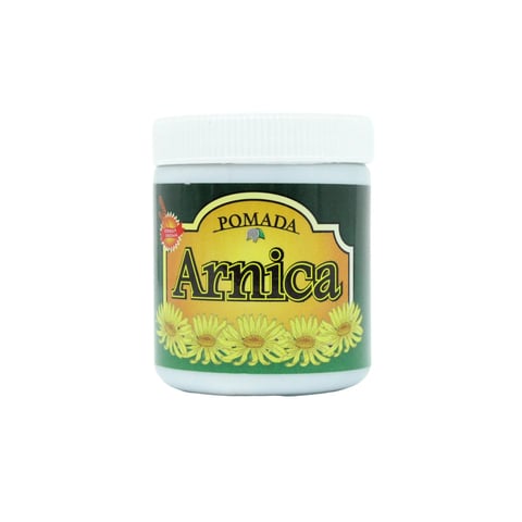 Jar of Pomada Arnica, a green herbal salve with white lid and yellow label featuring daisy flowers